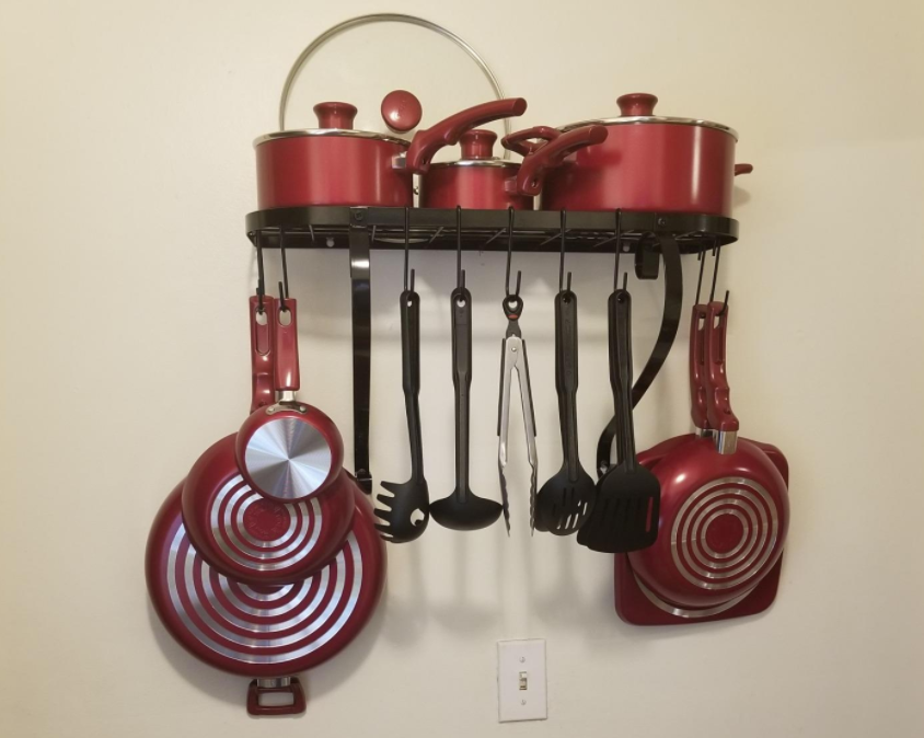 reviewer photo of the black rack holding various pots, pans, and utensils 