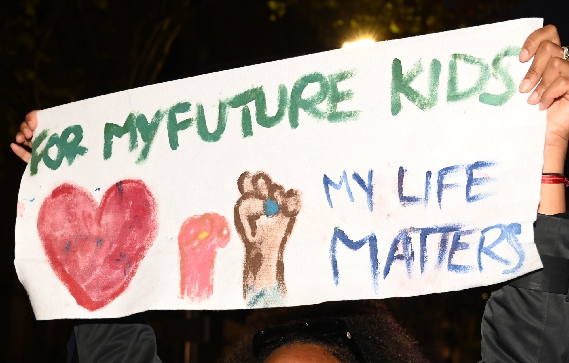 A protest sign reads &quot;For my future kids, my life matters&quot;.