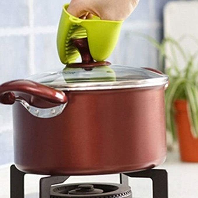 The silicone mitten being used to lift the hot lid of a pot