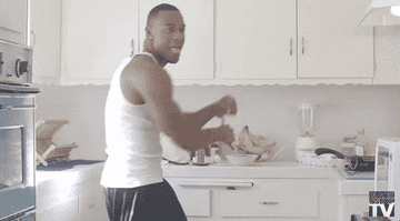 A person holding a spatula and dancing in the kitchen.