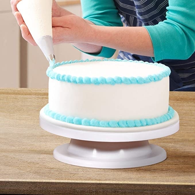 A person decorating a cake using the turntable.