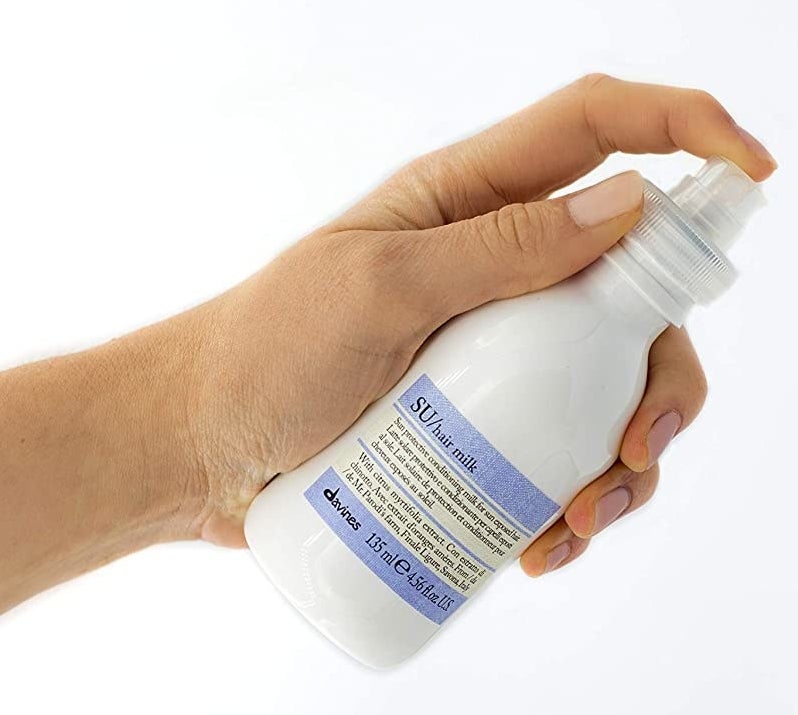 hand holding white bottle with spray nozzle