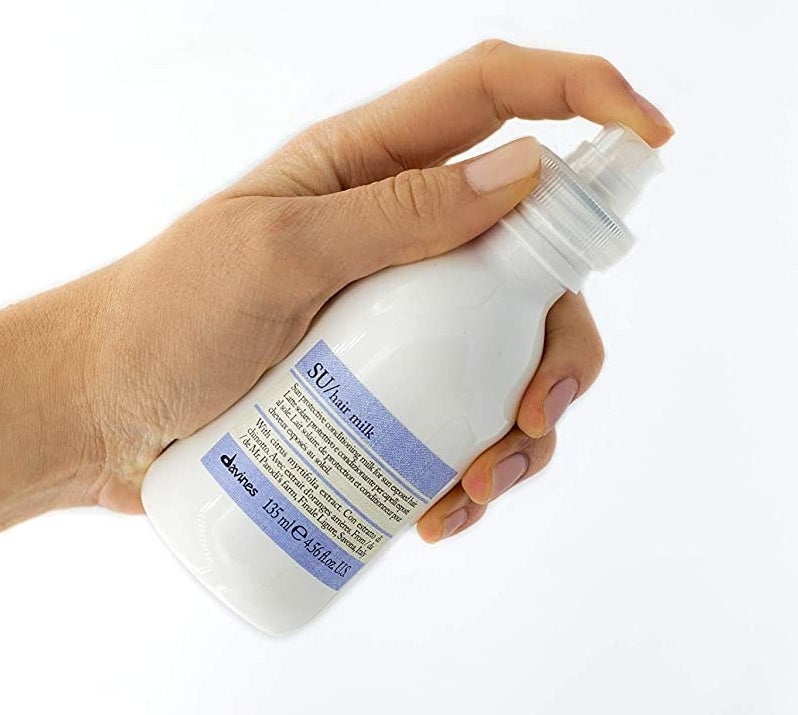 hand holding white bottle with spray nozzle