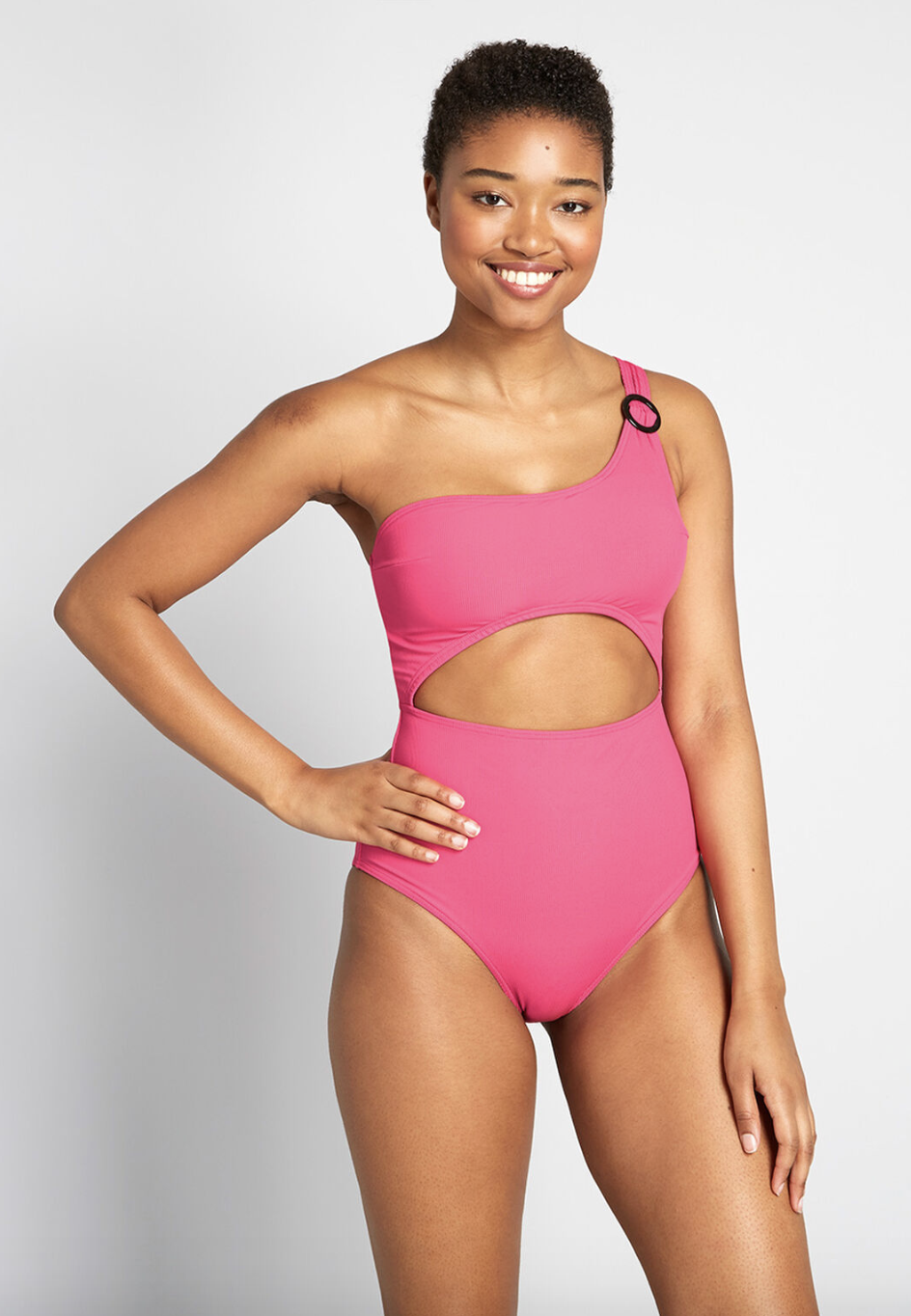 A model in an one-shoulder pink one-piece with a cut out at the rib 