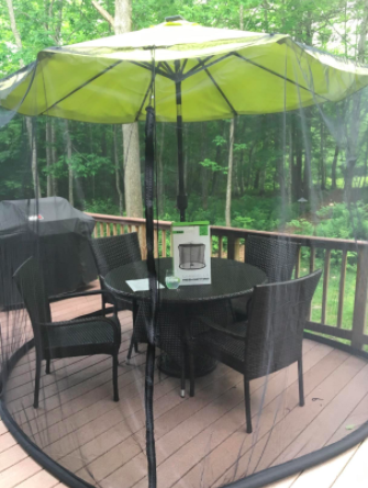 reviewer pic of the net on an umbrella on a deck with enough room for a table and four chairs inside
