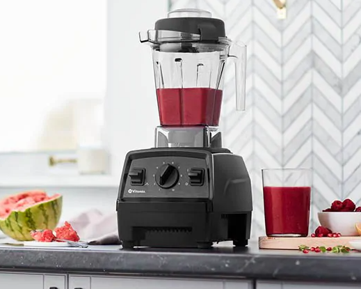 A black blender base with a clear plastic jar filled with a berry-based smoothie