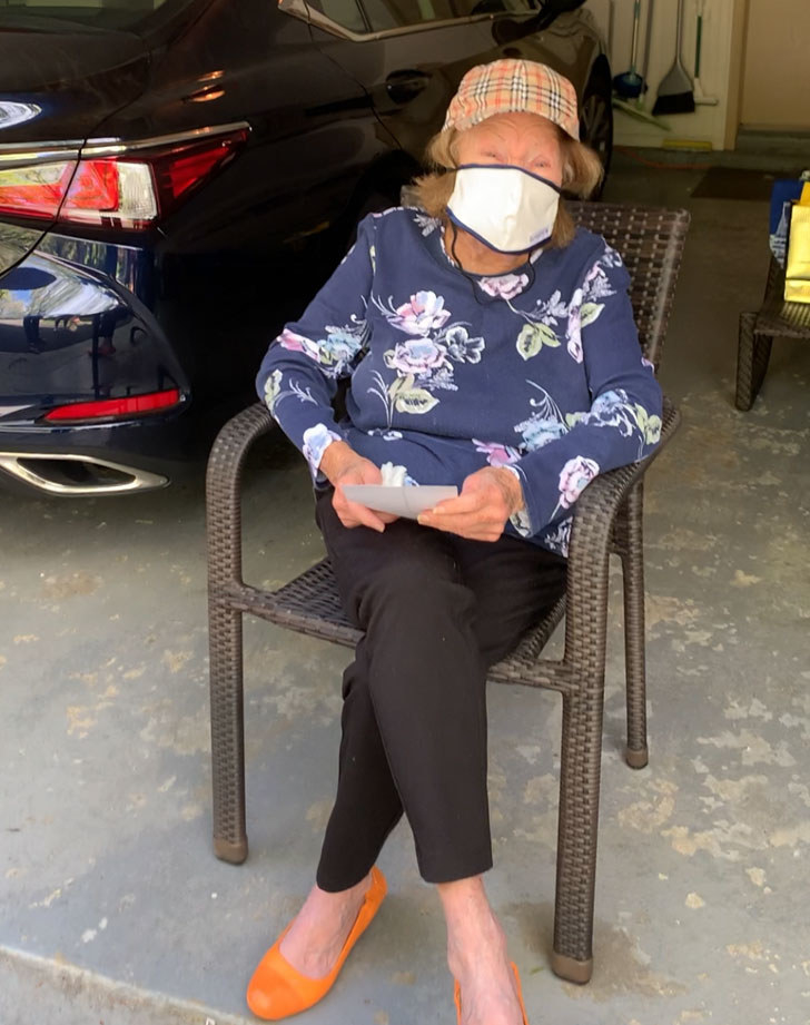 My grandma sitting in a chair in her garage wearing a mask.