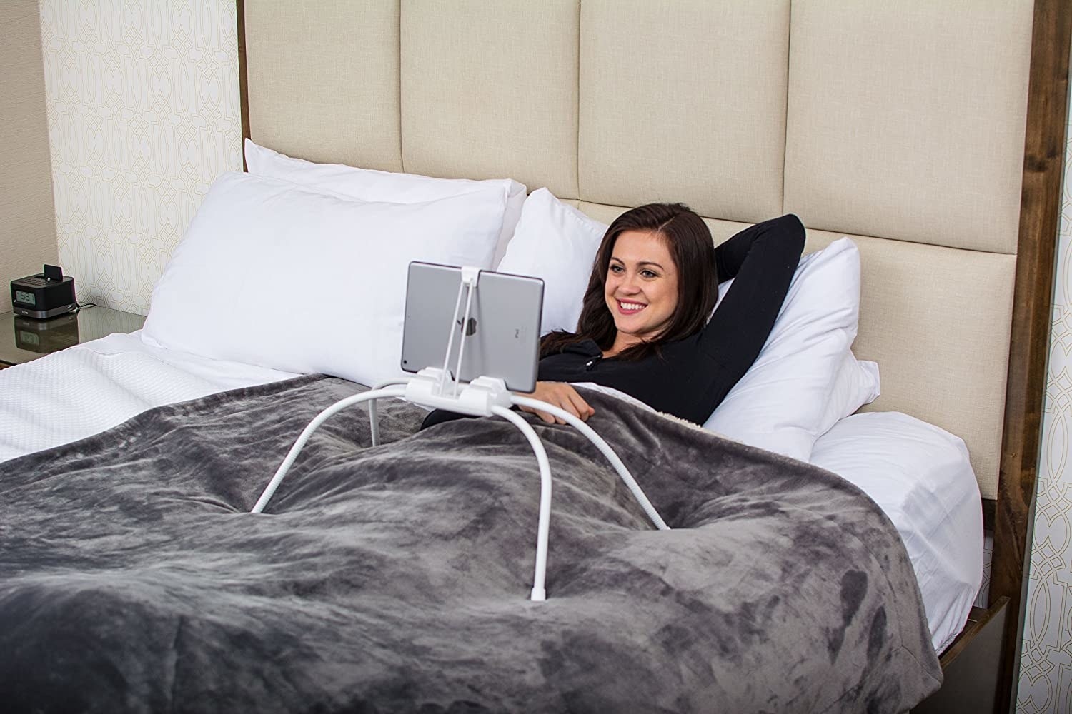person laying in bed with this product with four legs standing over them holding up a tablet