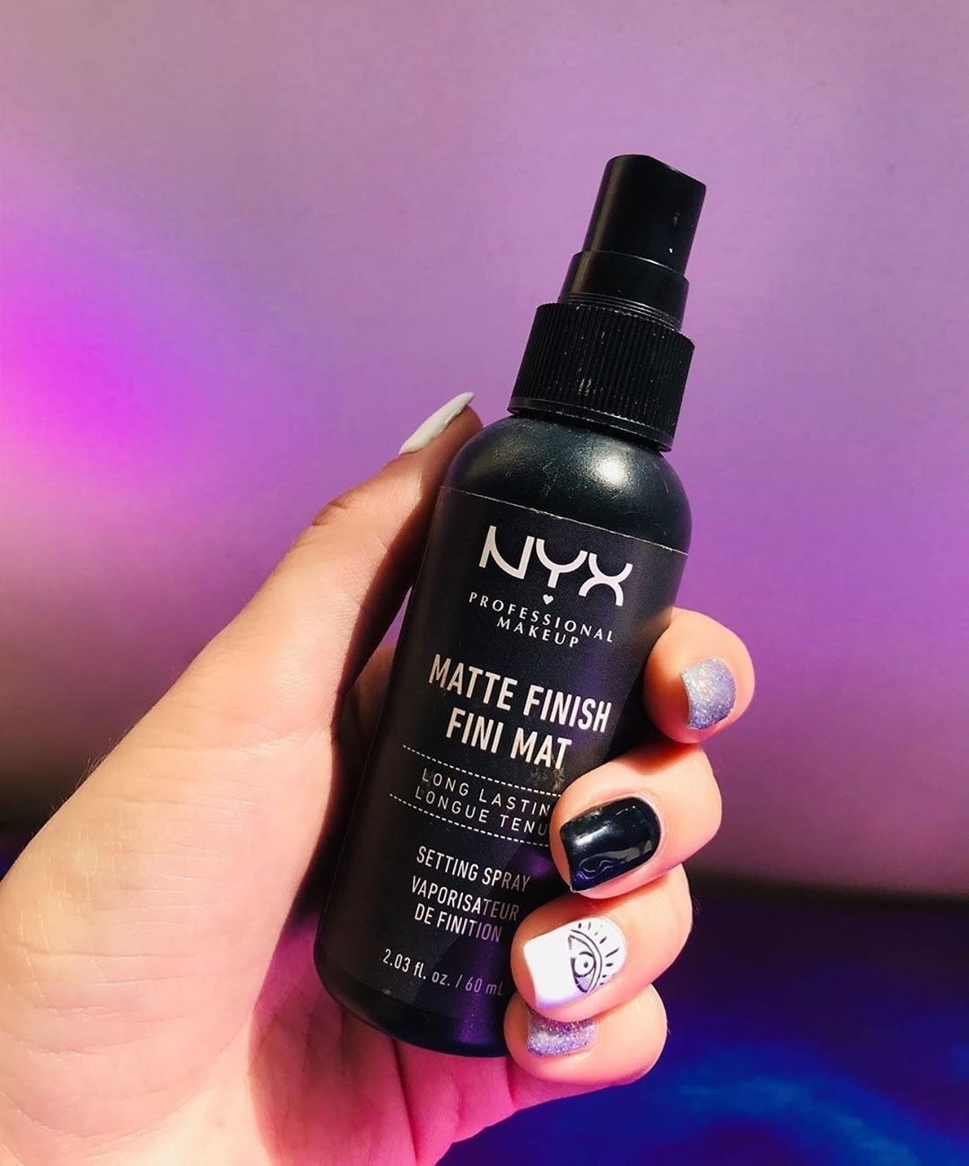 A person holding a bottle of NYX matte finishing spray