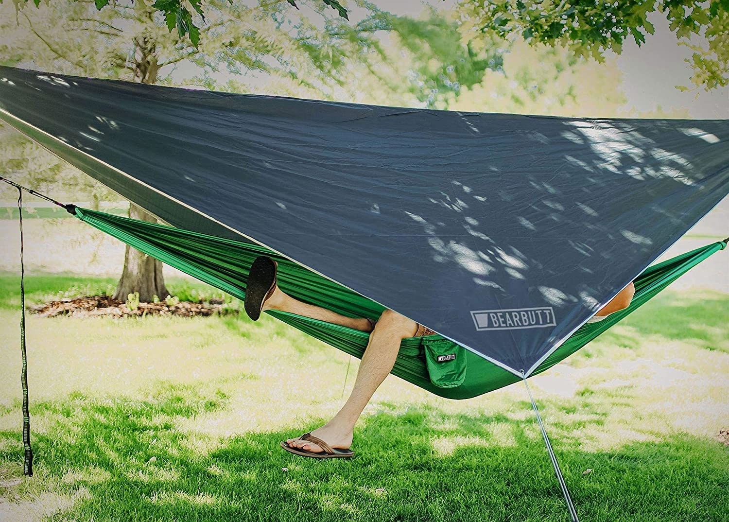 The fly stretching over a camping hammock that&#x27;s suspended between two trees