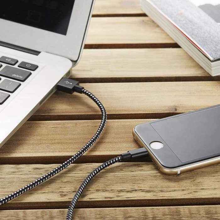 A charging cord plugged into a phone and into a laptop