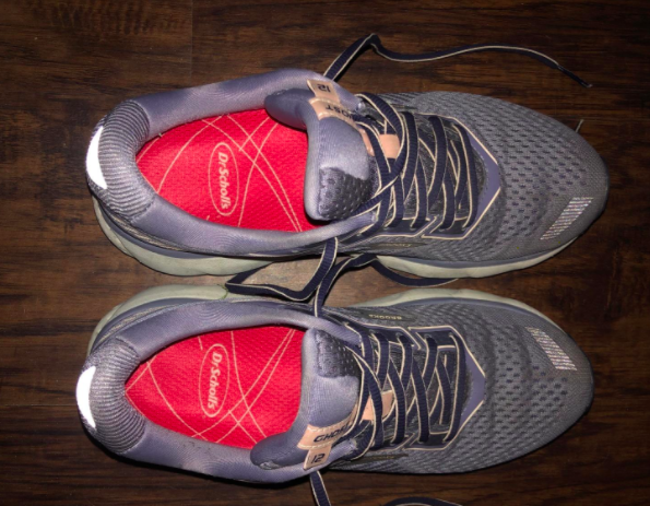 Reviewer shows pink Dr. Dr. Scholl’s running insoles in their purple athletic sneakers
