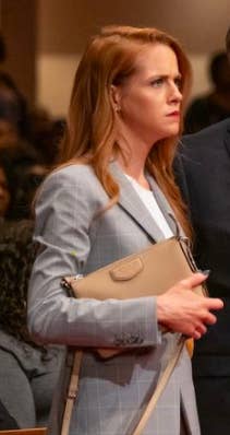 Valerie Jane Parker holds a clutch purse while facing the right