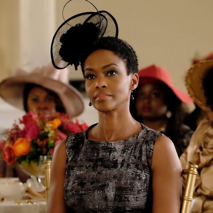 Kim Hawthorne wears a decorative hat while seated at a round table