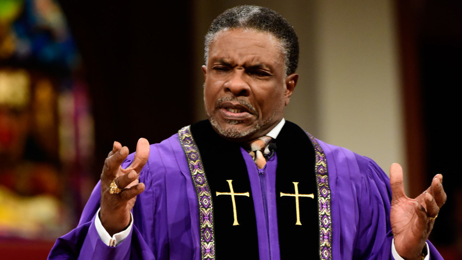 Keith David stands on the pulpit with his palms open and facing up