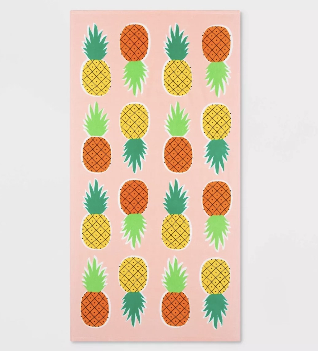 A pink towel with cartoon pineapples printed on it 