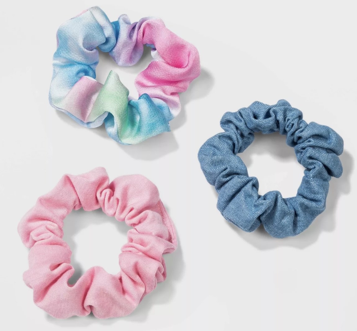 A tie-dye scrunchie, a blue scrunchie, and a pink scrunchie 