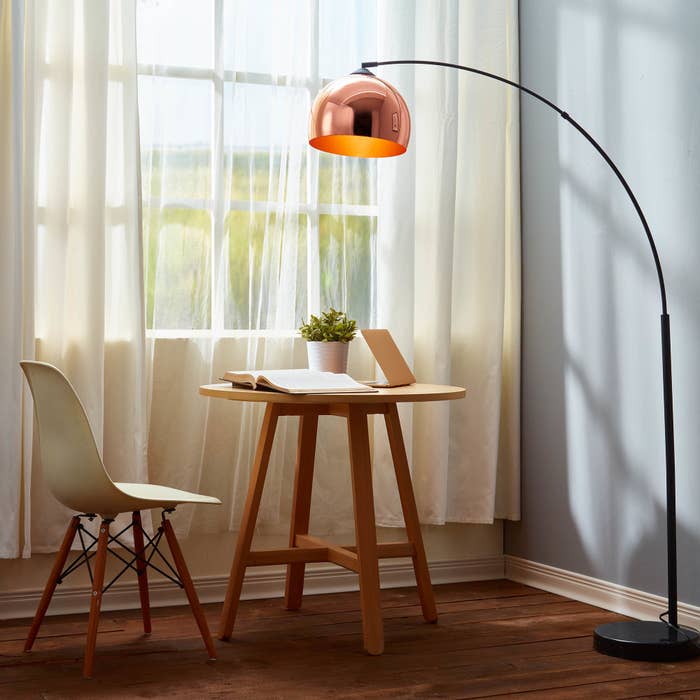 A chrome floor lamp with a curved black stand 
