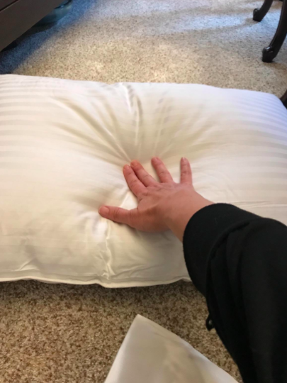 Reviewer places hand on white gel pillow to show its plushy texture