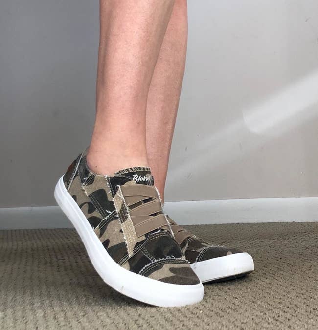 Reviewer wearing camouflage shoes with white soles 