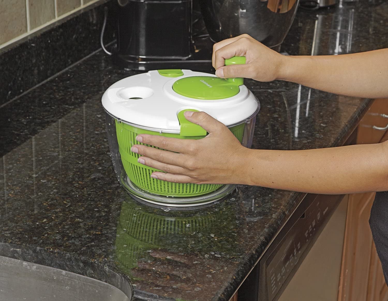 Hand turning the round crank to spin the salad spinner colander