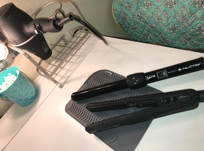 A reviewer photo of a curling iron and flat iron on the silicone mat