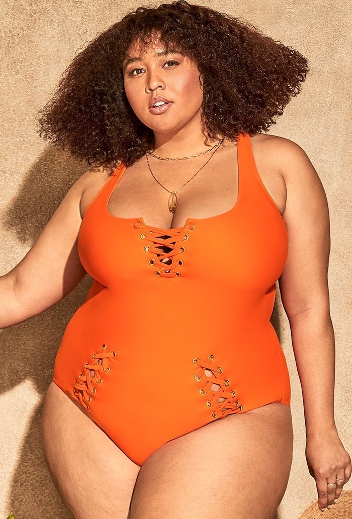 Influencer GabiFresh wearing an orange one-piece swimsuit with lace-up details 