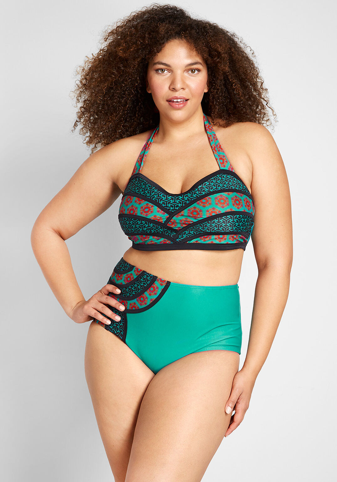 a model wearing the bathing suit top with four pattern areas showcasing two different green designs with red and black accents