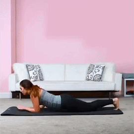 A person lays on their stomach, then lifts their chests up, keeping their forearms pressed to the ground in a sphinx stretch