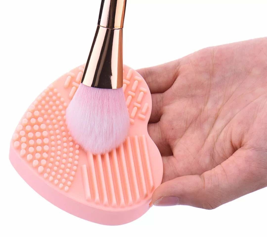 A makeup brush being cleaned on a pink silicone cleaning pad
