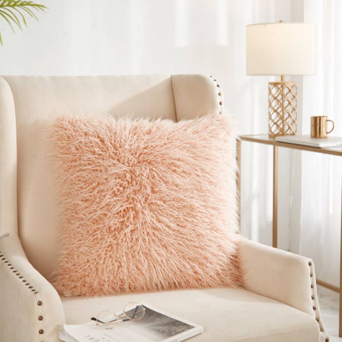 a fuzzy pink pillow placed in a white chair
