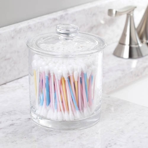 a glass container with a nice glass lid filled with q-tips