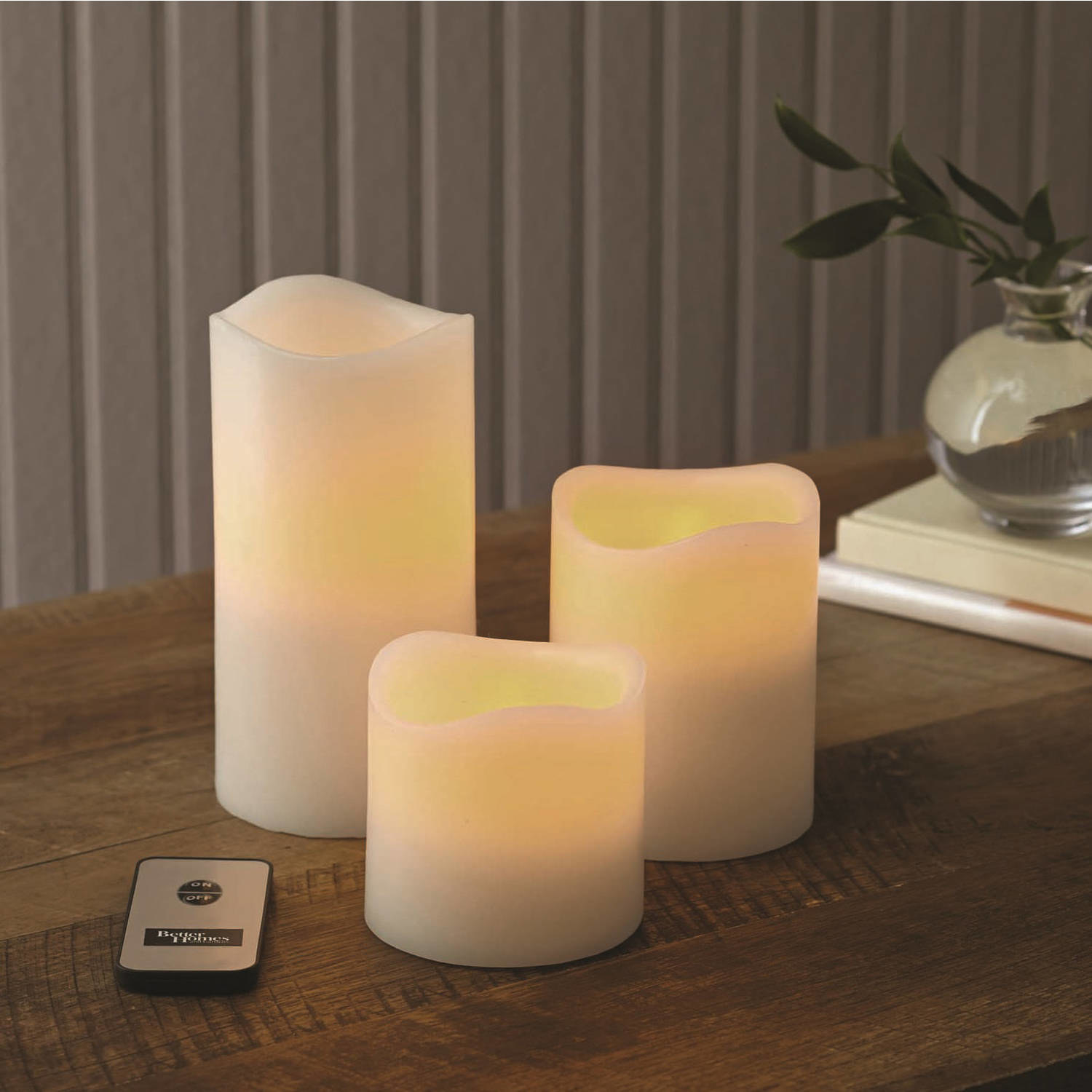 a set of three off white fake candles with a soft glow and a remote