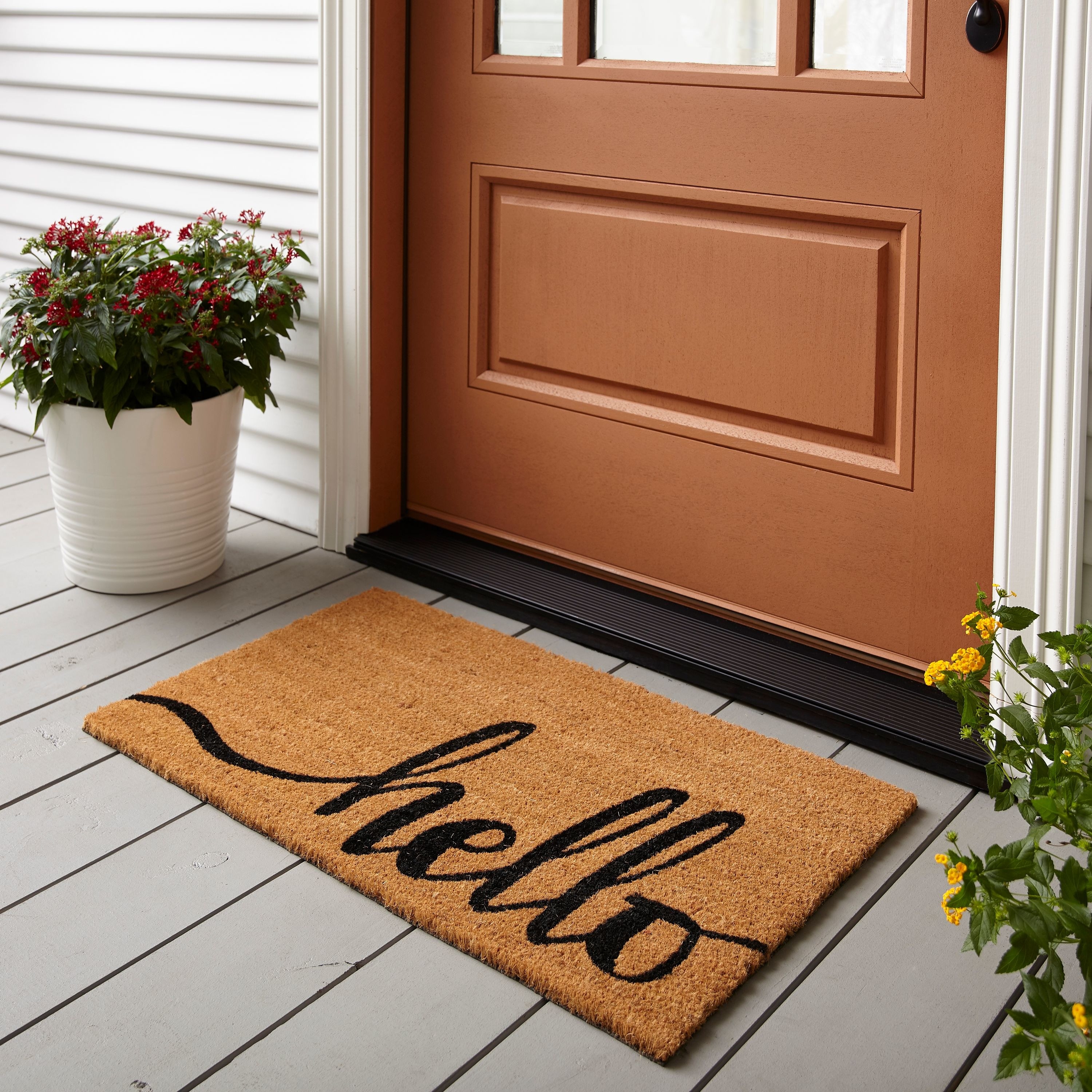 a tan thick welcome mat with &quot;hello&quot; written on it in black script