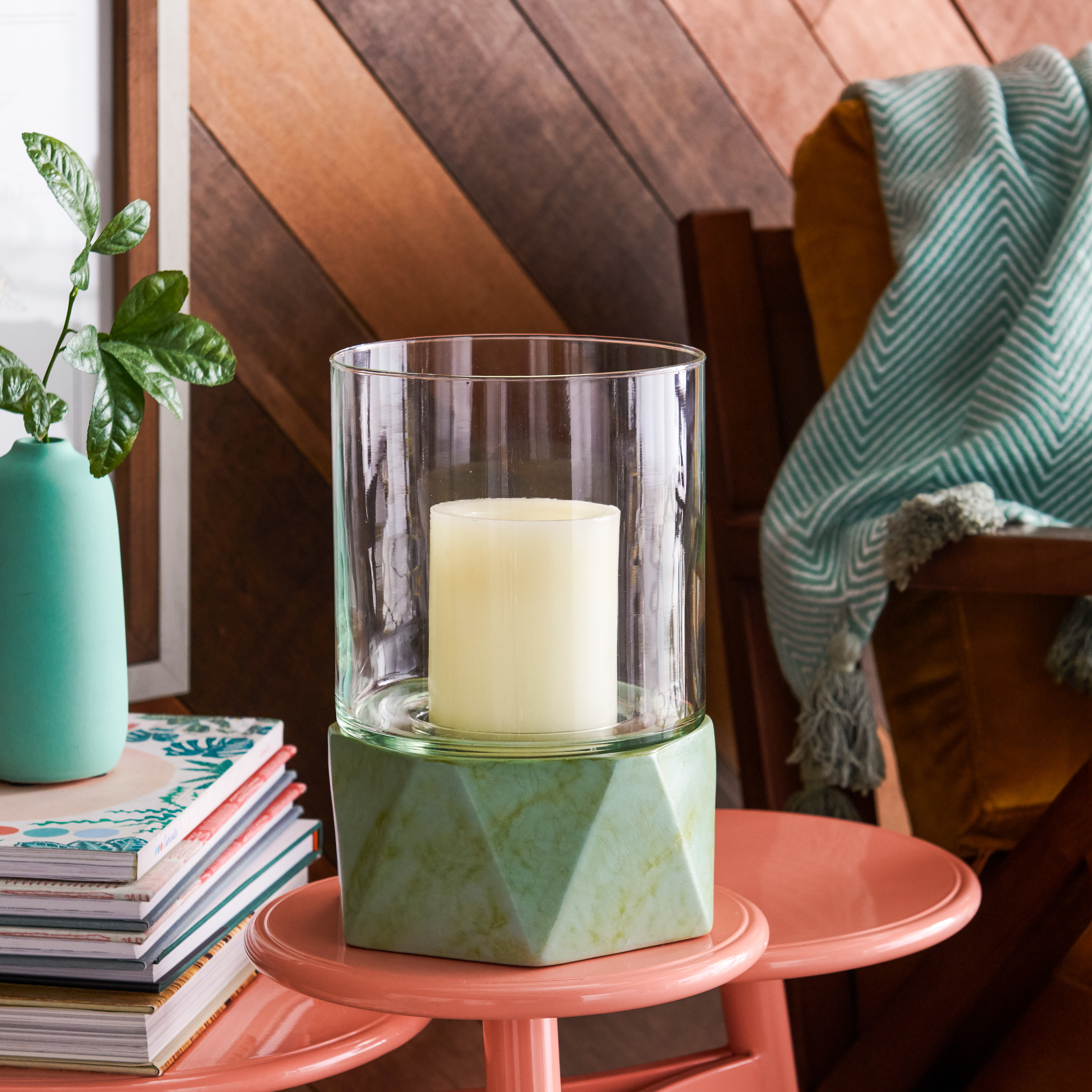 a see through glass cylinder around a candle with a geometric shaped green marbled base