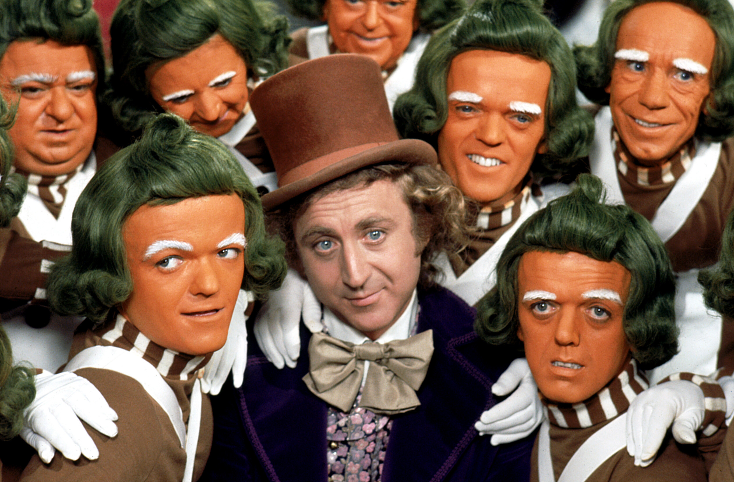 Willy Wonka surrounded by Oompa Loompas