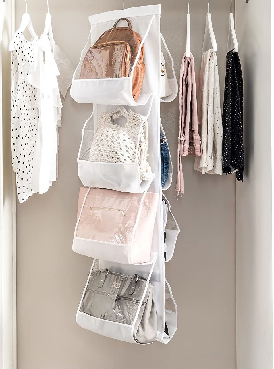 Eight handbags inside the handbag organizer in a closet
