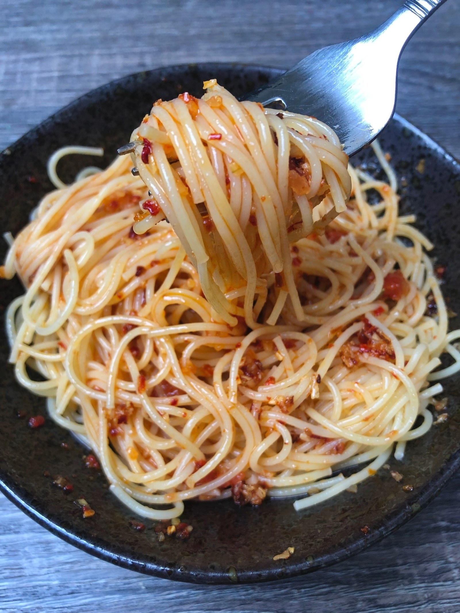 A bowl of spaghetti with chili onion crunch condiment.