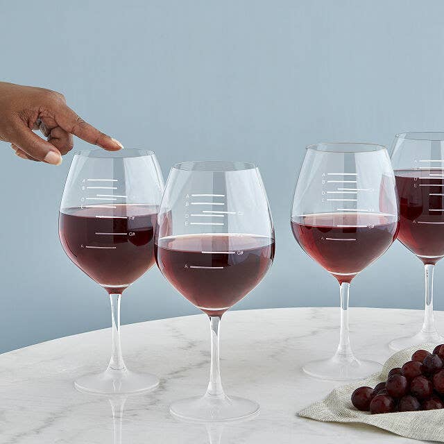 Four musical wine glasses filled to different notated major scales and a finger running along the rim of one of them