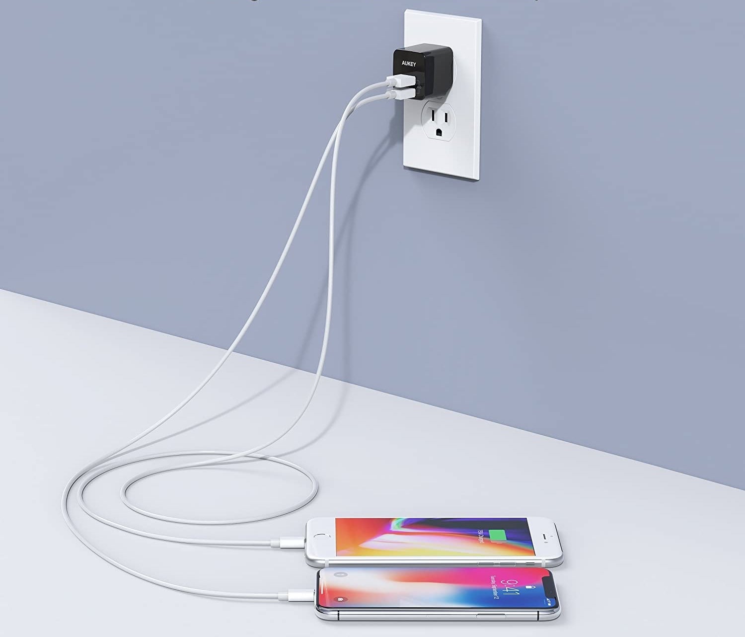 A charger plugged into the wall charging two phones