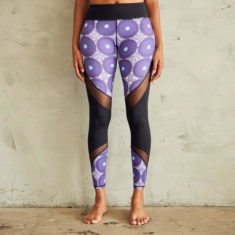 Model wearing the leggings with a thick black waistband, diagonal mesh panels and black panel in the middle by the knee and a purple circular pattern on the rest of the leg