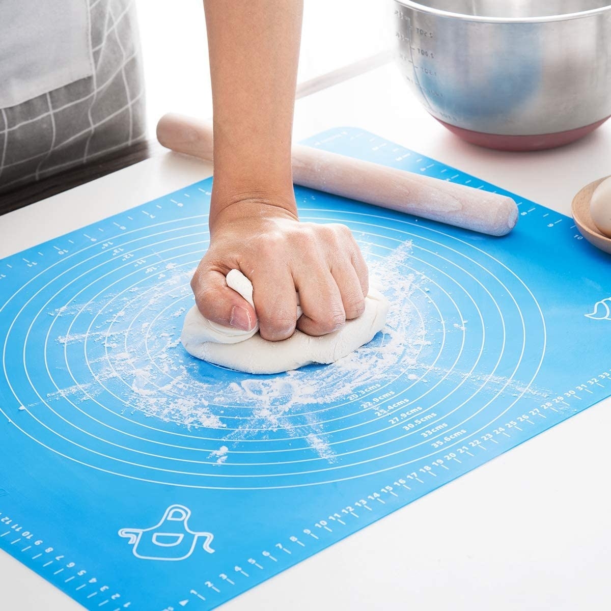 A person smashes a ball of dough onto the centre of the silicone baking mat
