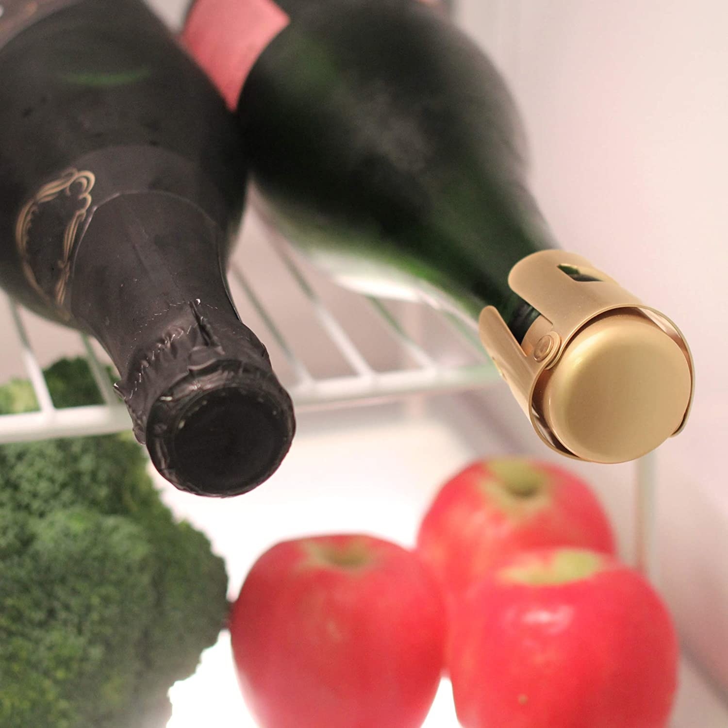 A bottle of sparkling wine capped with the bottle stopper rests on a fridge shelf