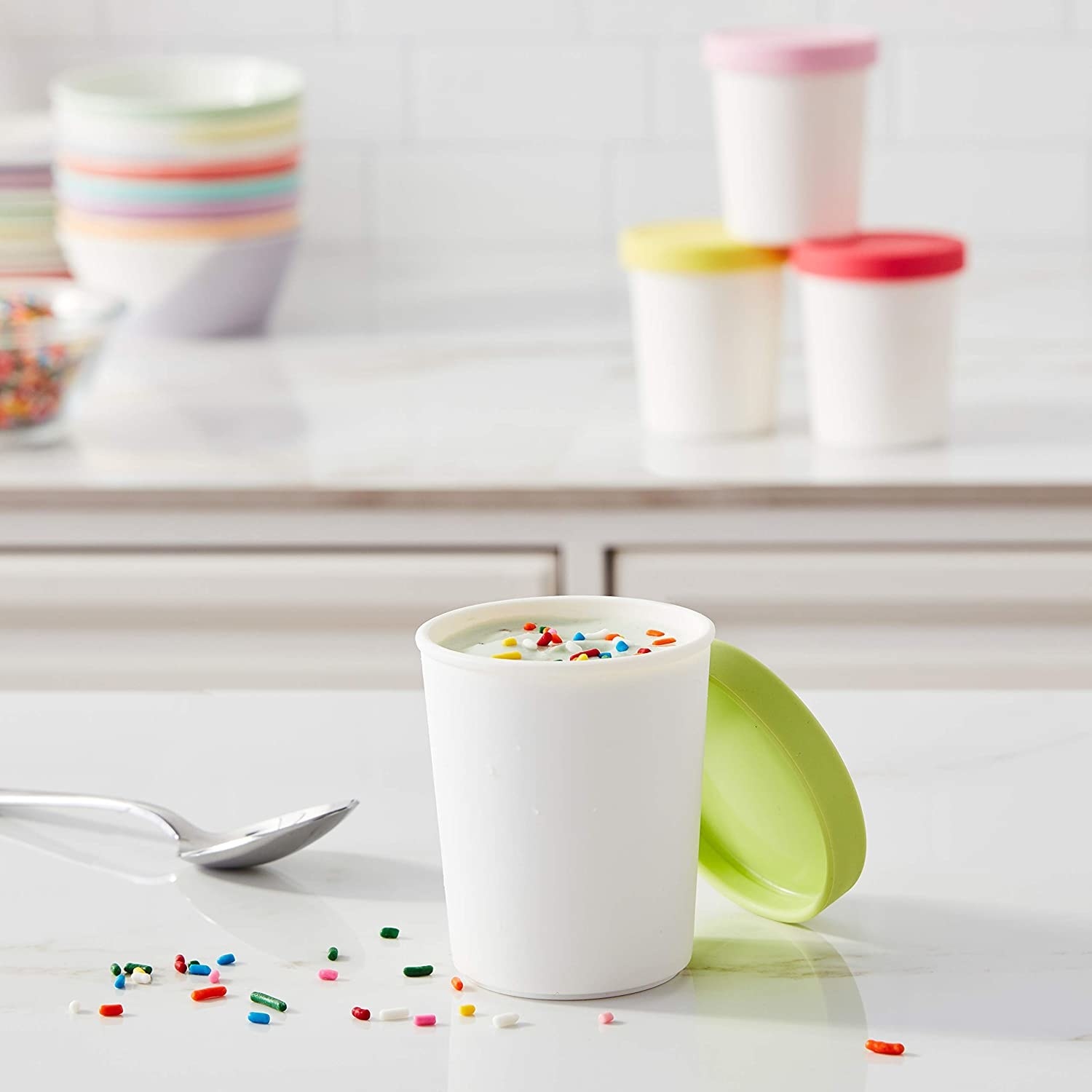 A mini ice cream tub full of vanilla ice cream sits on a countertop with scattered sprinkles around it