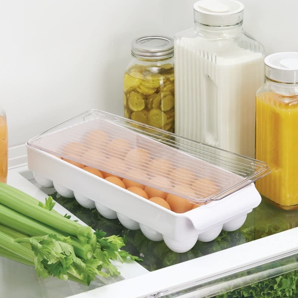 The egg organizer rests on a fridge shelf where fresh brown eggs are visible inside