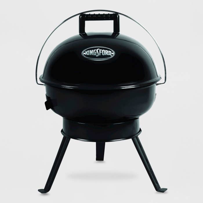 A shiny black three-leg charcoal grill