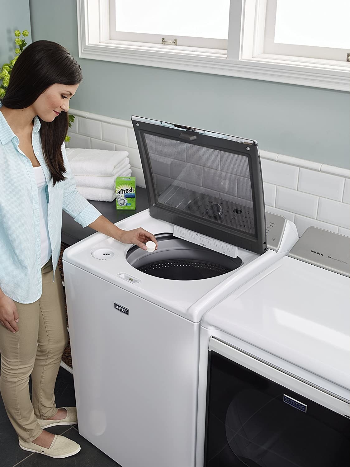 A person puts a tablet in the washer