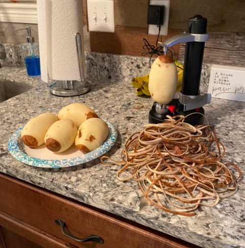 reviewer pic of potato peeler in use with stack of peels on kitchen countertop beside a plate of four peeled potatoes