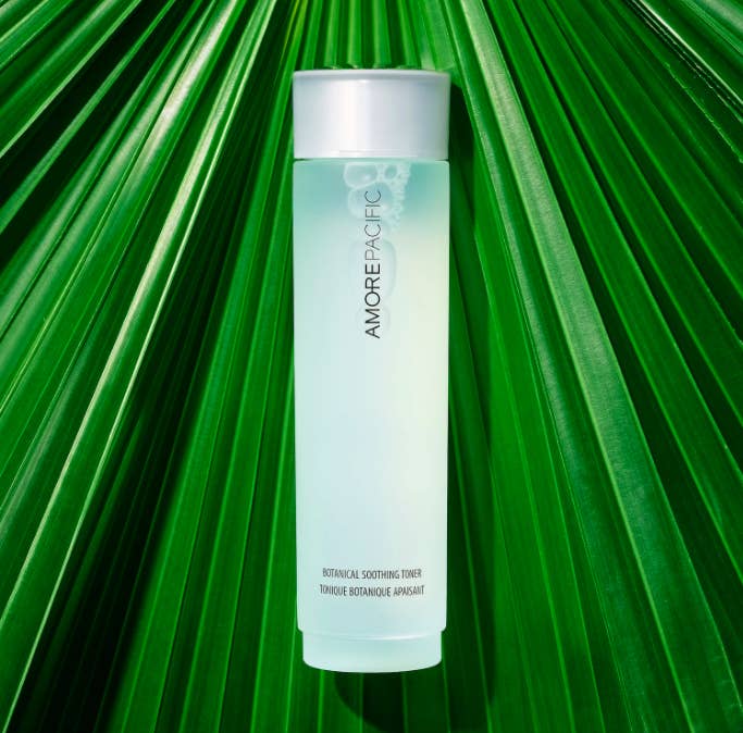 A bottle of the botanical soothing toner laying on top of green foliage