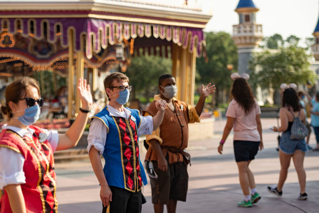 Disney cast member greet visitors while wearing protective masks